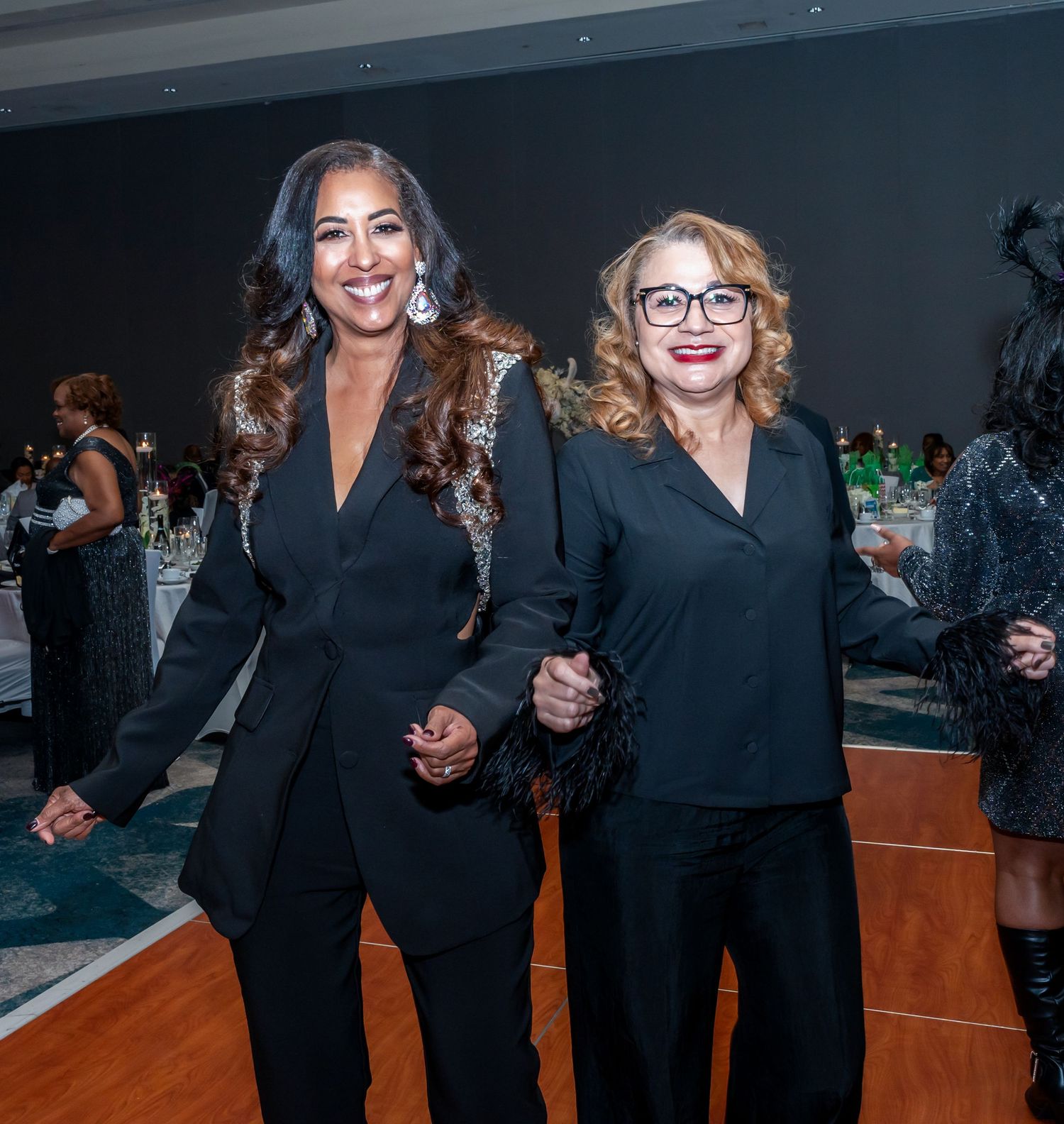 Professional gathering with attendees in black formal wear mingling in an event space.