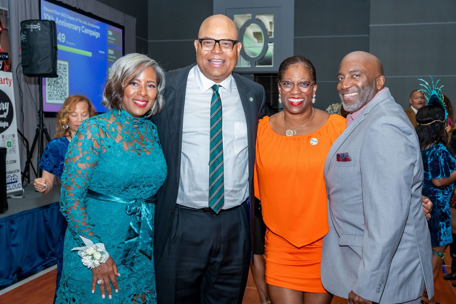 Professional gathering with attendees in orange, teal and gray business attire.