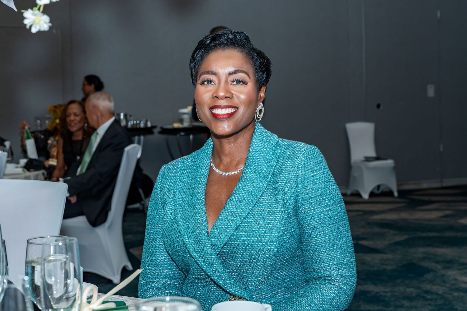 Guests in bright teal and formal attire networking at an elegant indoor event.