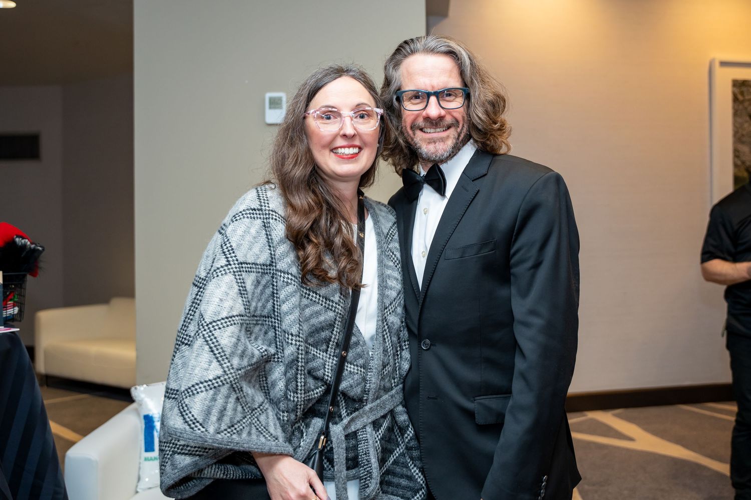 Couple in formal attire share a cheerful moment at an event.