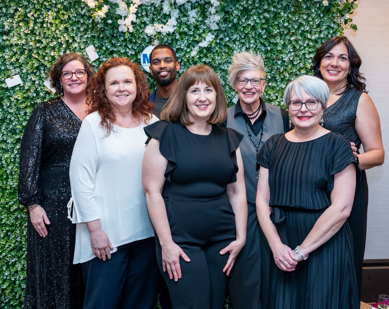 Group photo of attendees in formal black and white attire standing together at an elegant event.