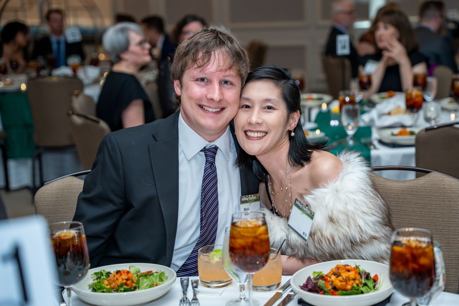 Couples seated at dining tables with iced beverages during formal celebration.