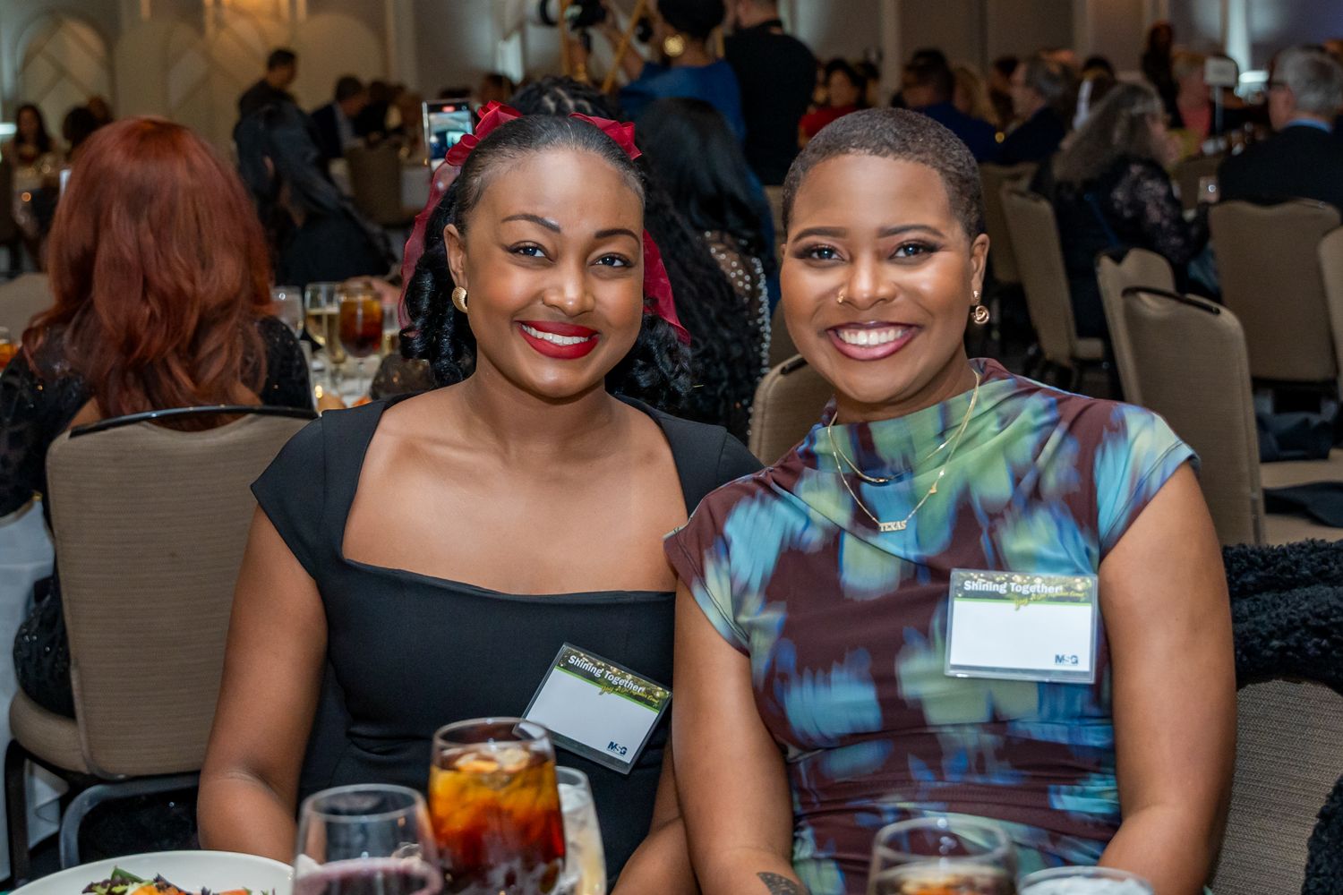Event guests in formal attire enjoying dinner and conversation at decorated tables.