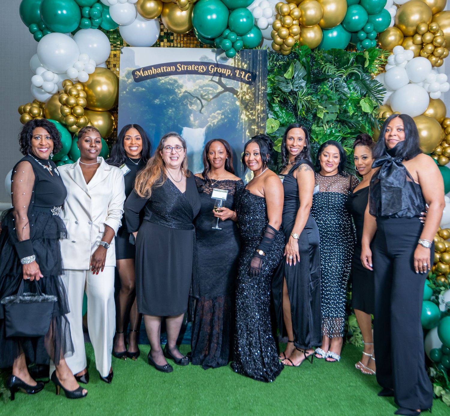 Formal event group photo with decorative green and gold balloon display.