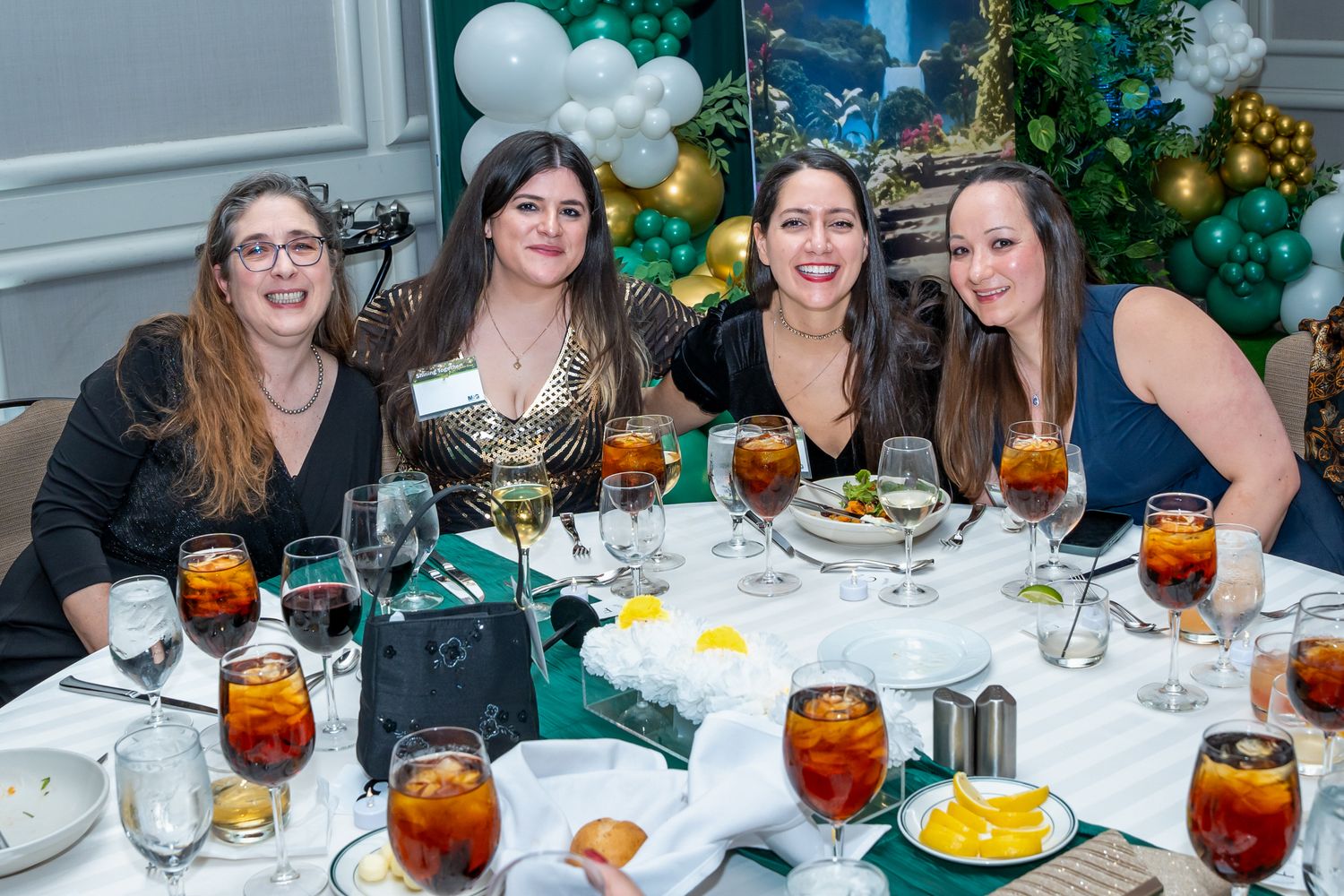 Group of friends enjoying drinks and conversation at an elegant dinner party with festive decorations.