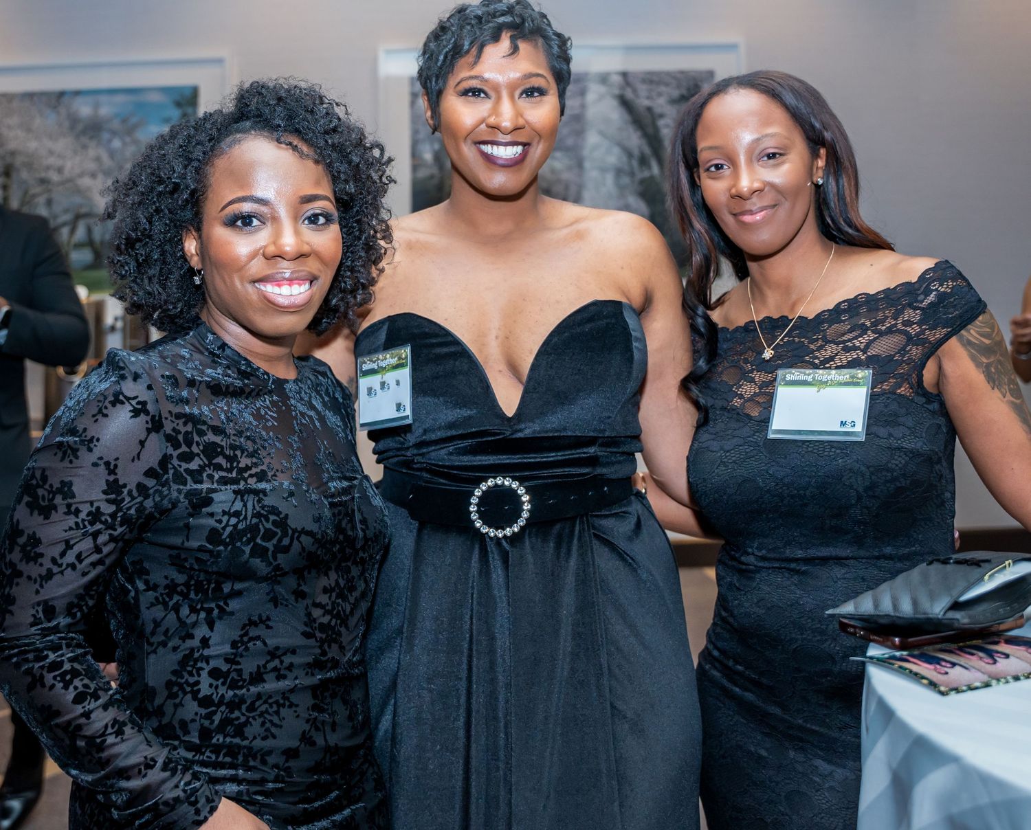 Group photo of attendees wearing elegant black dresses at a formal evening event.