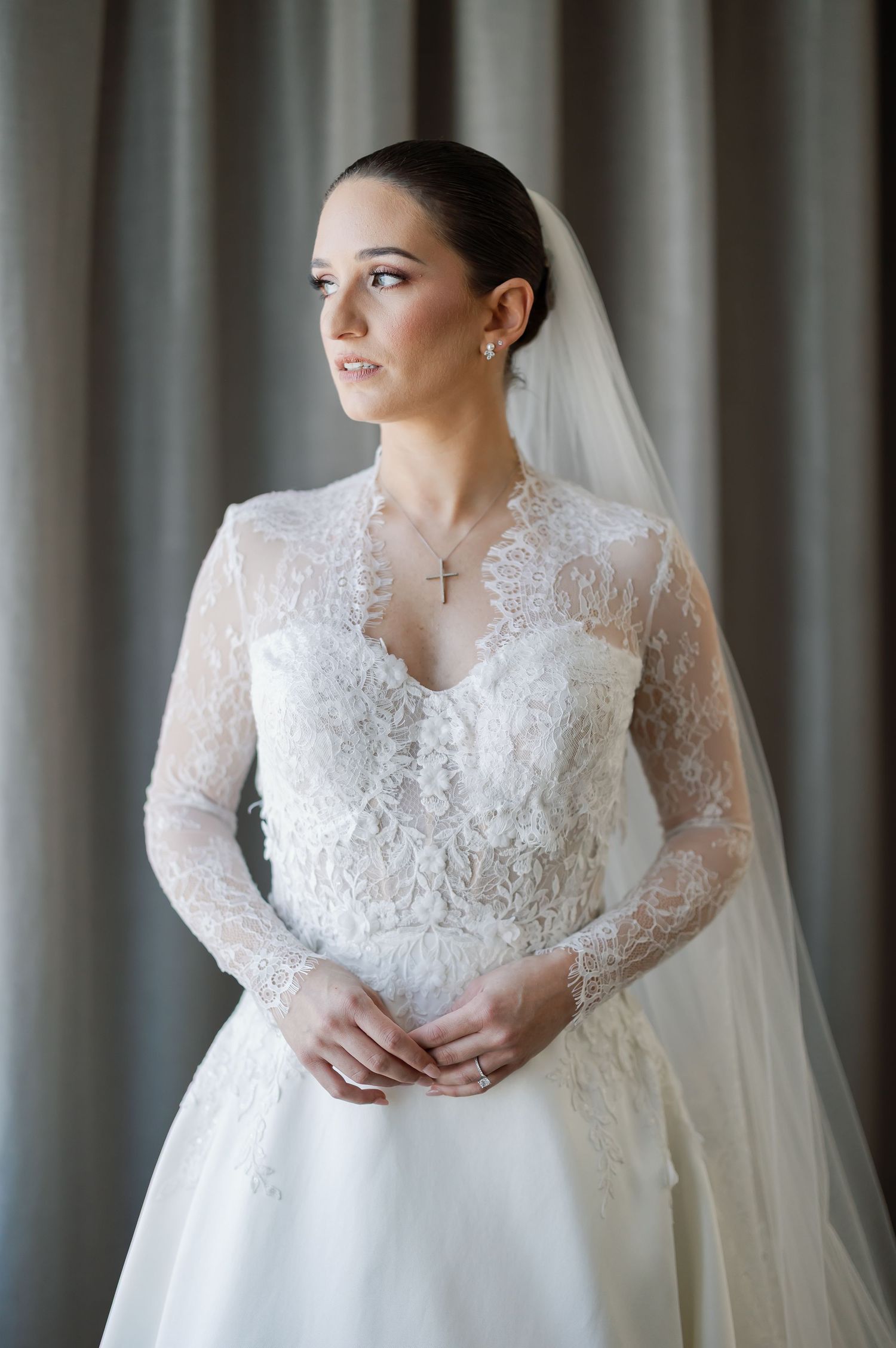 A woman in a long white wedding dress stands alone in a room.