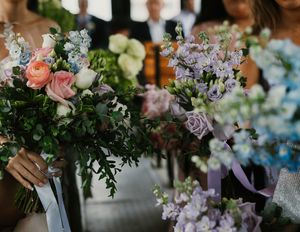 Bridesmaids holding colorful bouquets of pink, lavender, and green flowers at an outdoor wedding.