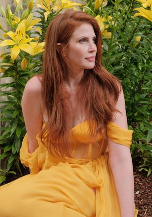 A yellow off-shoulder sundress billows gracefully against lush green foliage in an outdoor garden setting.  Dallas Arboretum