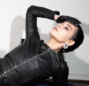 A model in an edgy black leather jacket poses dramatically against a light background.