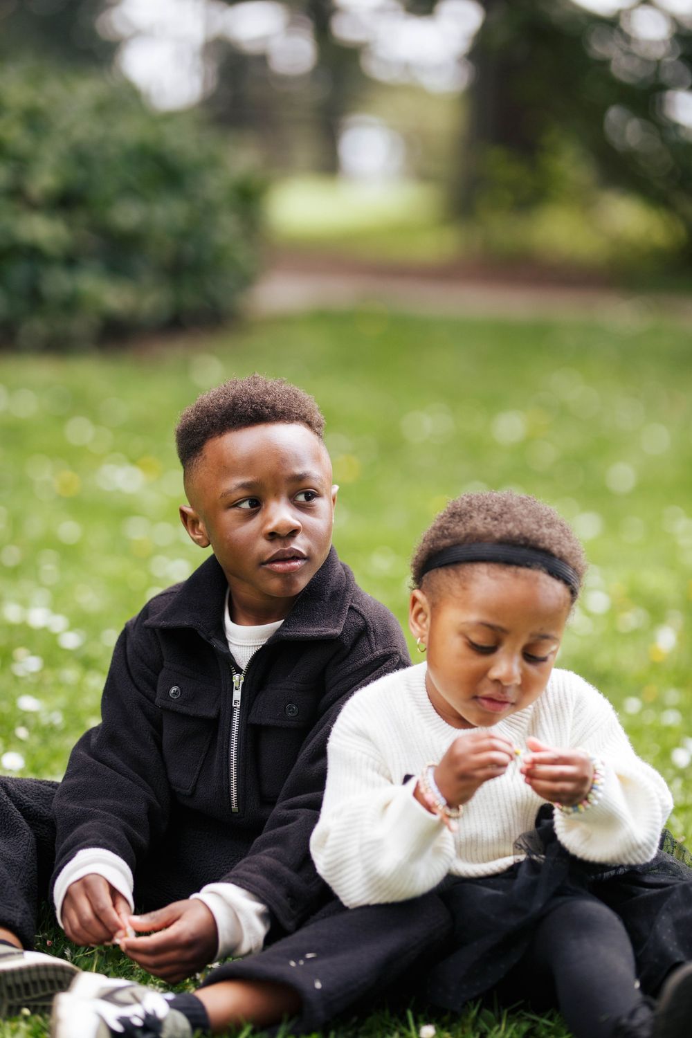 Everett WA family photographer: a young boy and girl sit on the grass at a family photo session in the Spring at the Evergreen Arboretum