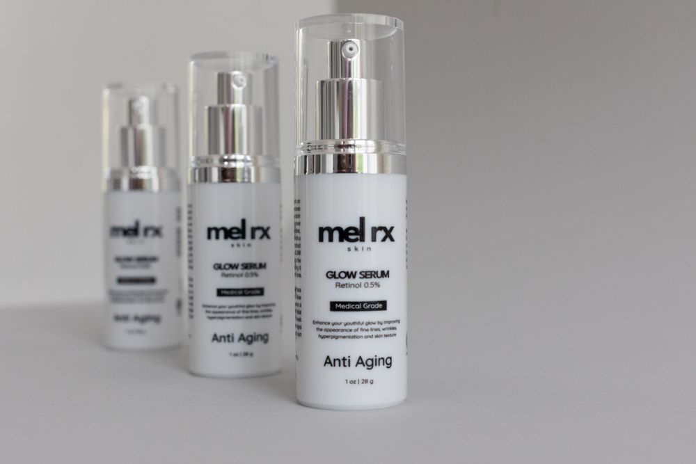 Three white anti-aging skincare bottles from the Melrx beauty line arranged on a plain white surface.
