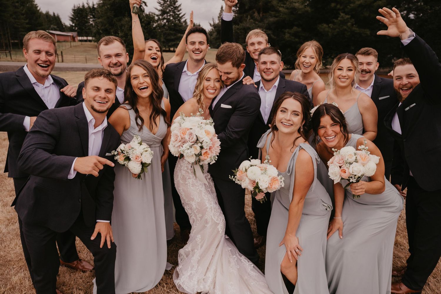 Wedding party in coordinated gray and black formal attire poses outdoors during celebration.