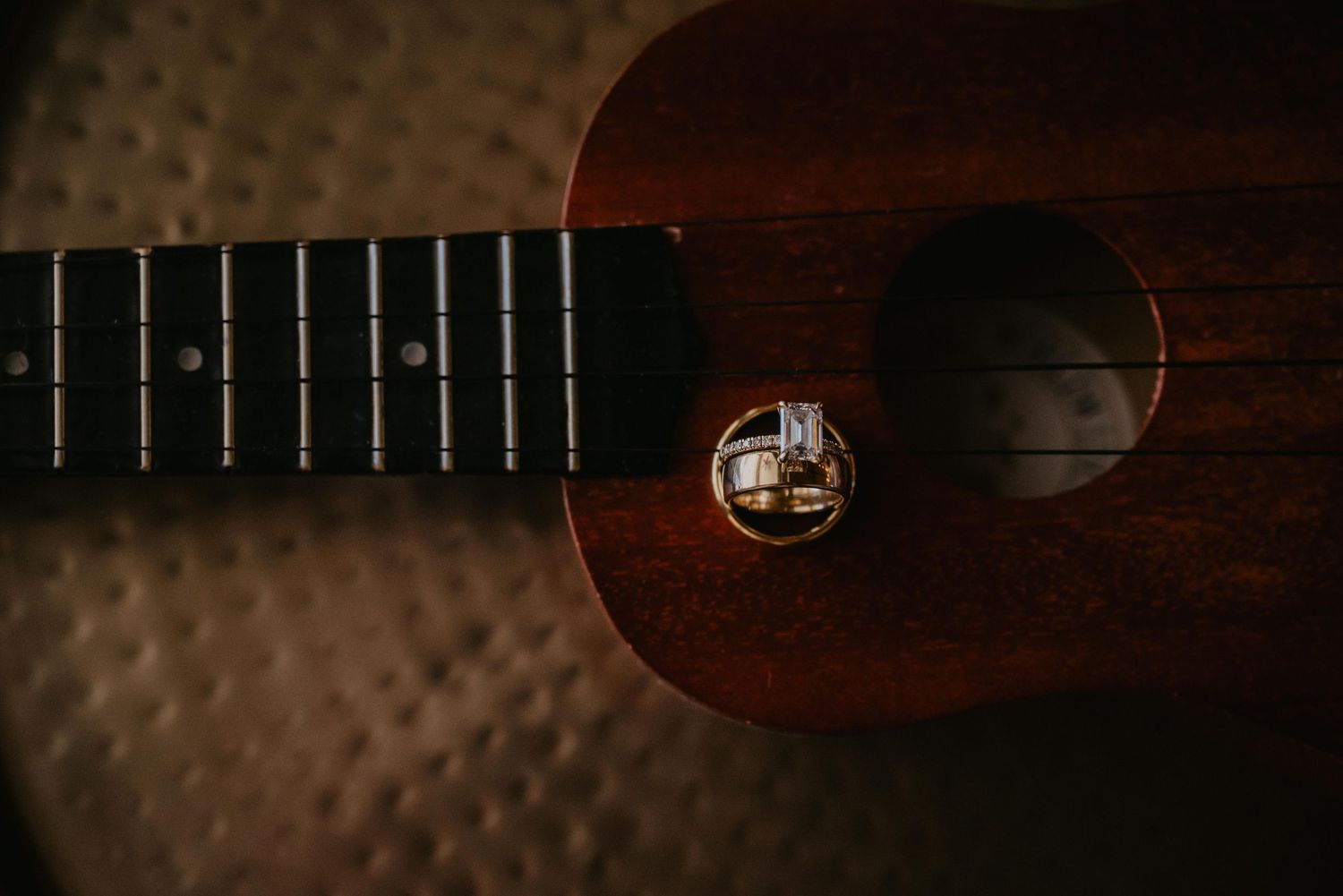 Close-up view of three guitar headstocks with detail of tuning pegs and strings against a dark background.