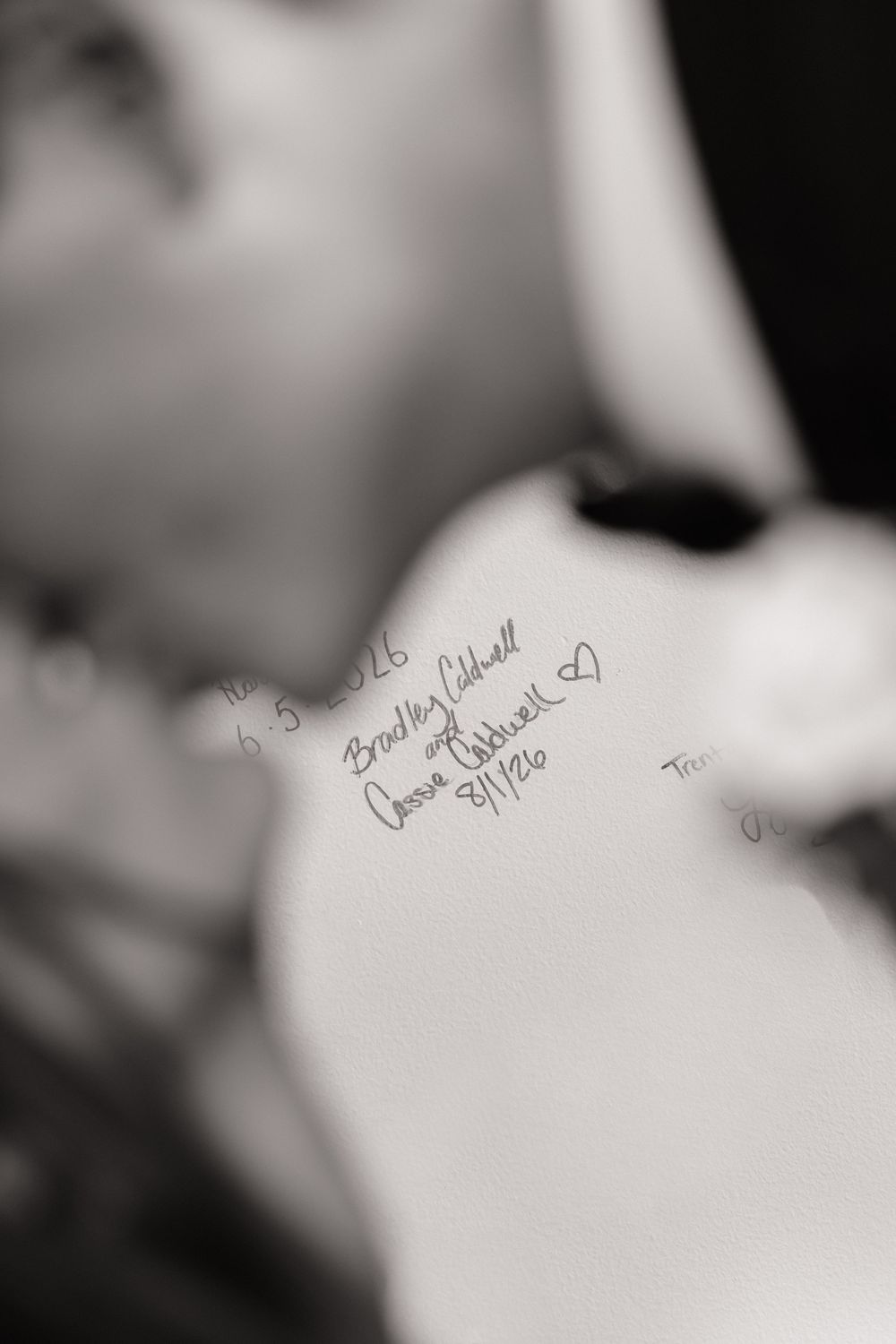 Black and white photo of signatures written on skin, including names Bradley Caldwell and Joanne Caldwell with a heart.