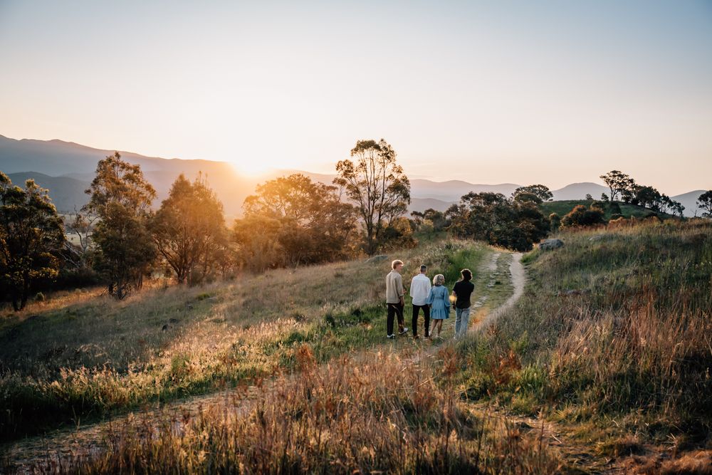 Small group walking together on a hillside trail during sunset with eucalyptus trees in the background.