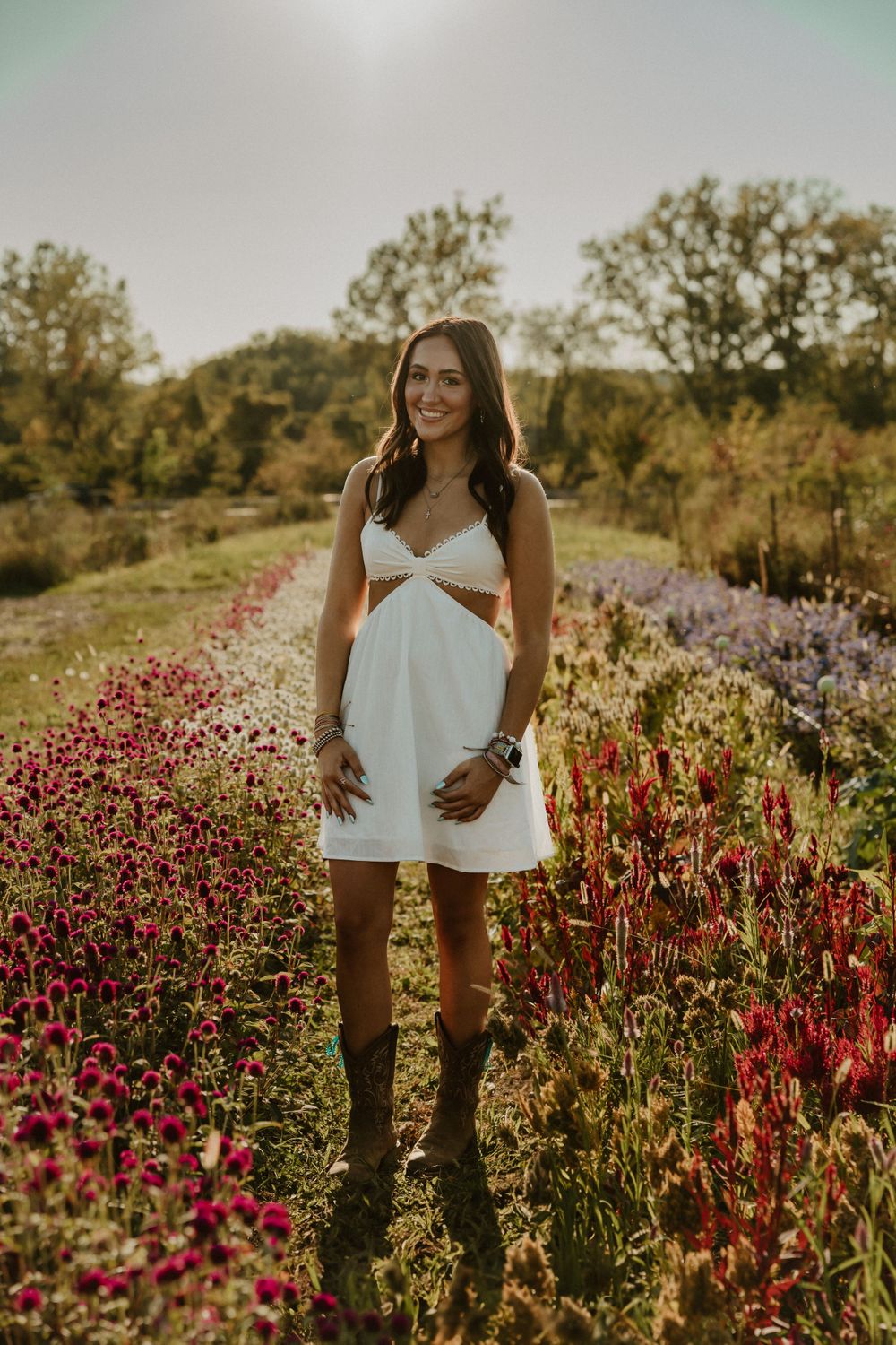 White cutout dress styled with boots among colorful wildflowers at sunset.