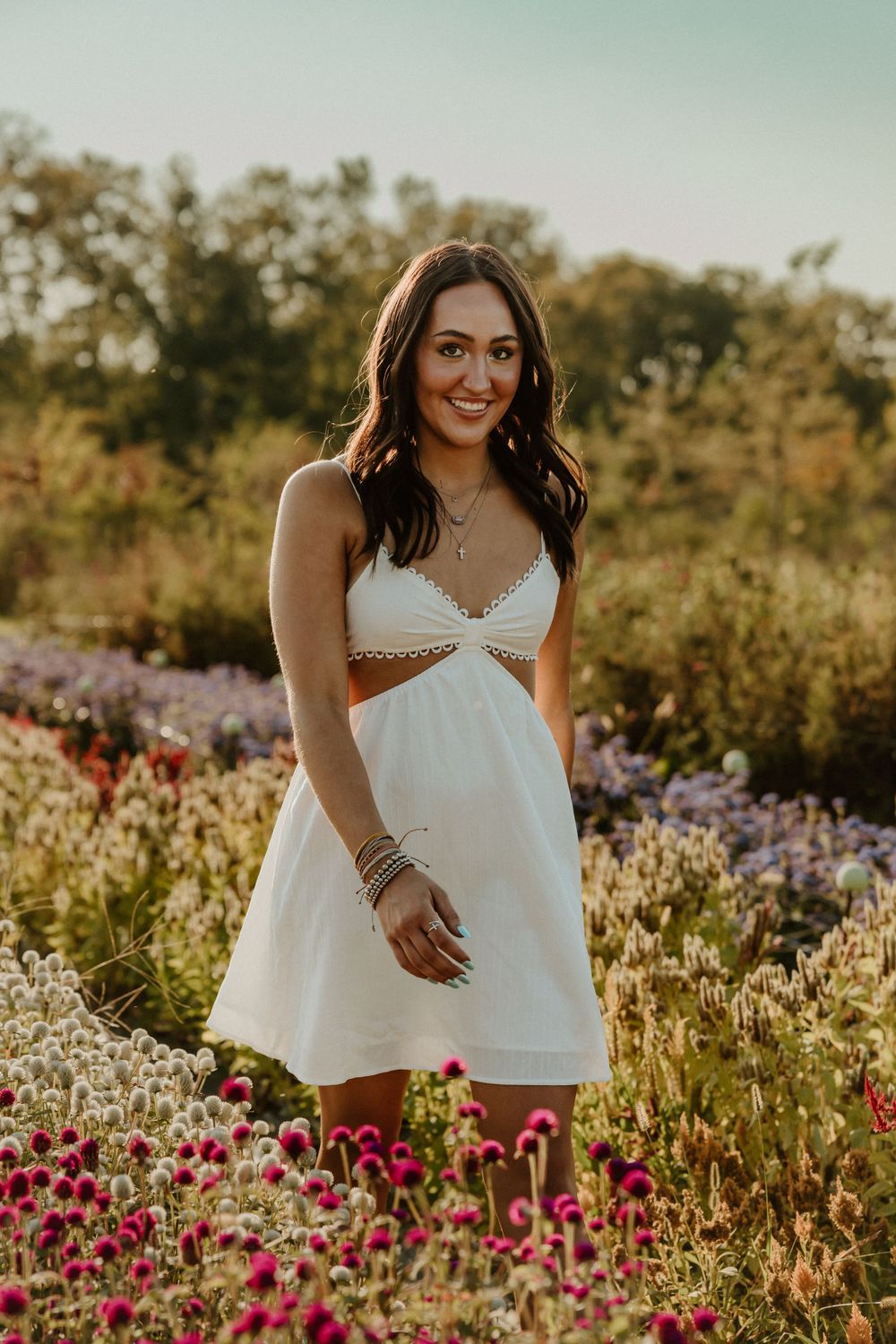 A summery portrait in a white dress standing among vibrant wildflowers at golden hour.