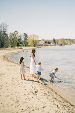A family spends a peaceful afternoon playing on a sandy beach shore near the water on a calm sunny day.