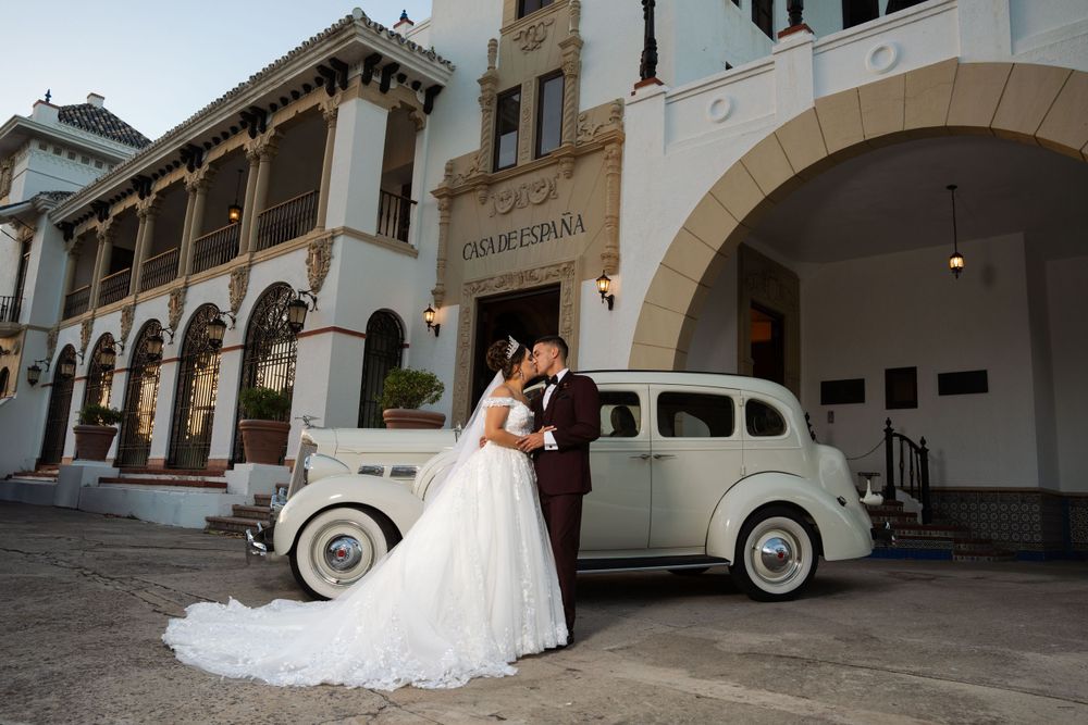 Elegant wedding photo with a vintage car and Spanish colonial architecture in the background.