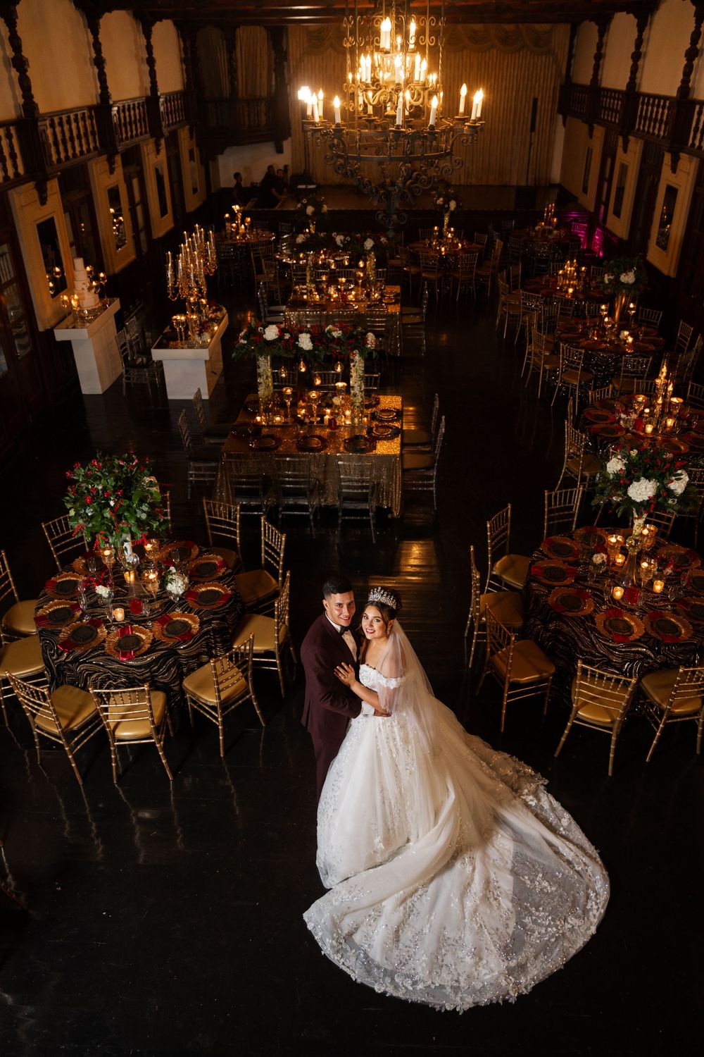 Overhead wedding reception shot in grand hall with chandeliers and romantic candlelit atmosphere.