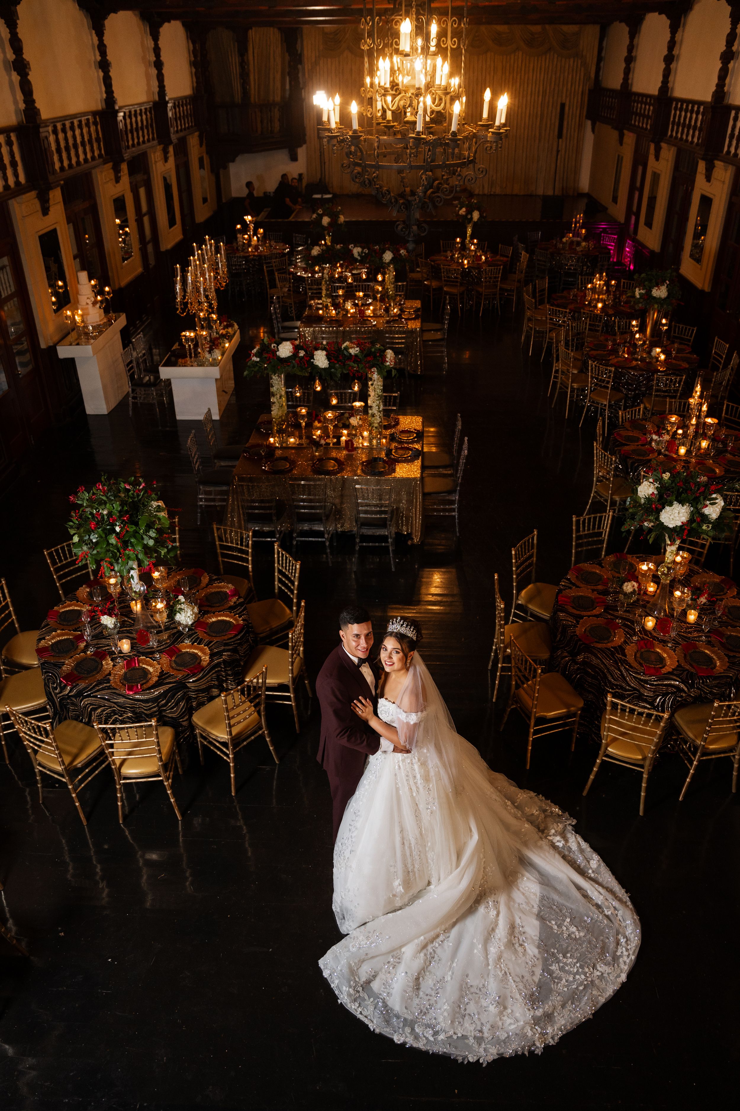 Overhead wedding reception shot in grand hall with chandeliers and romantic candlelit atmosphere.