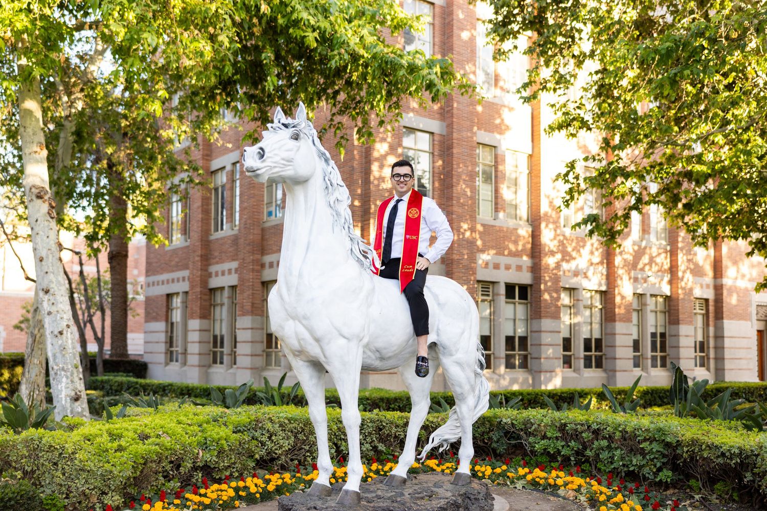 A decorative white horse statue stands in front of a classic brick university building.