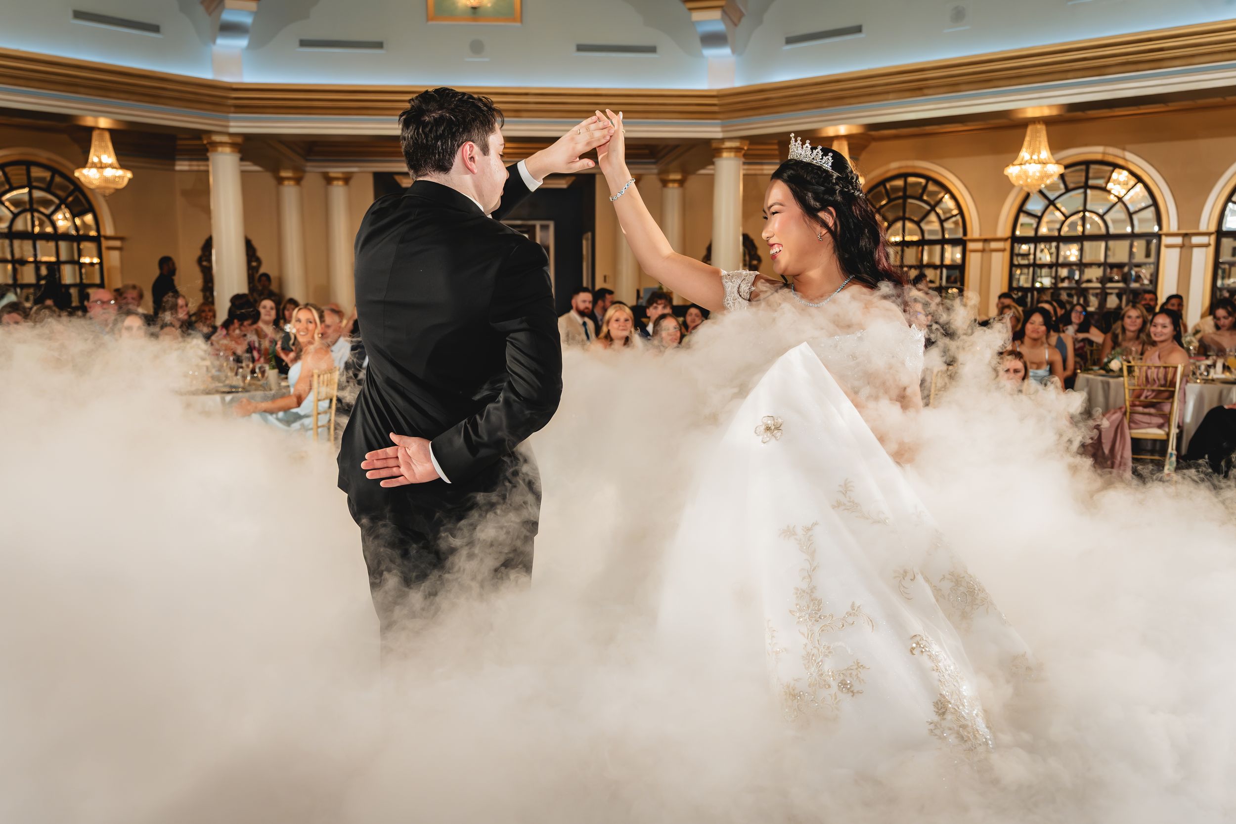 Bride and groom share first dance surrounded by dramatic fog effects at elegant wedding reception venue. Wedding Photography, Photographer