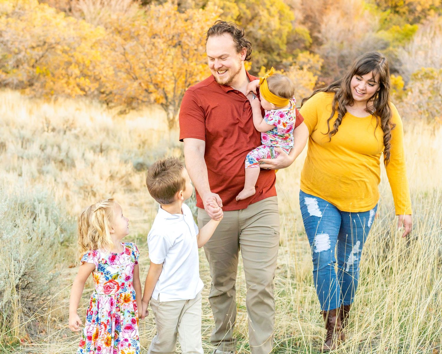 A family enjoying outdoor portraits in tall grass with autumn mountain scenery at Hidden Valley Park, Utah.