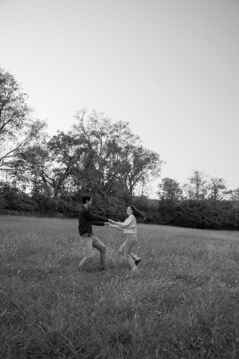 Playful, black and white shot of couple spinning in an open field