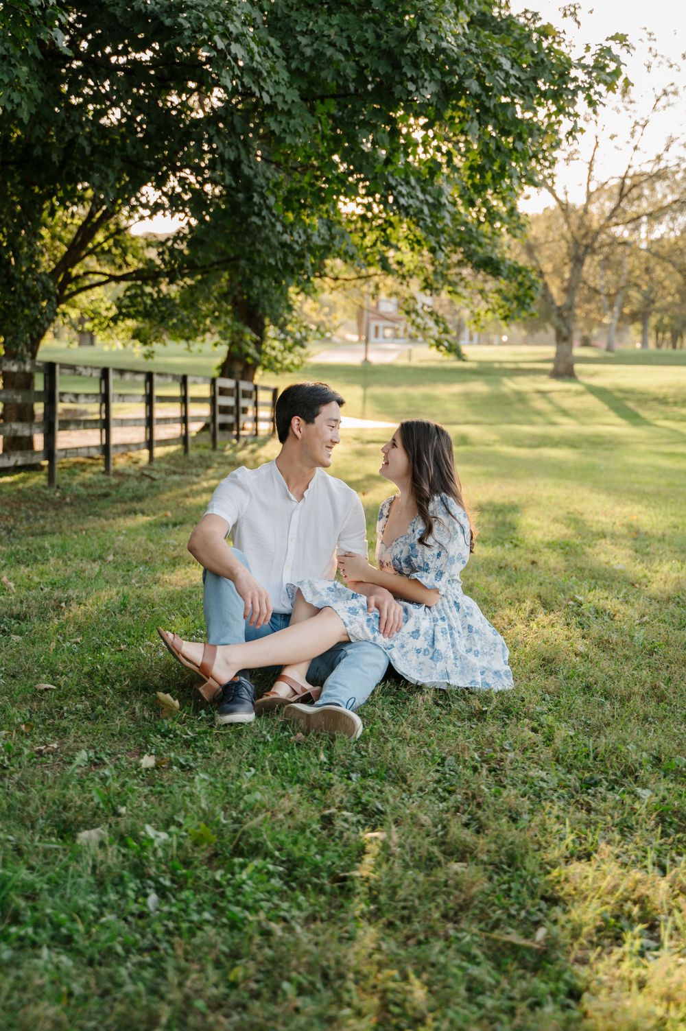 Couple sits side by side in a bright, sunny field