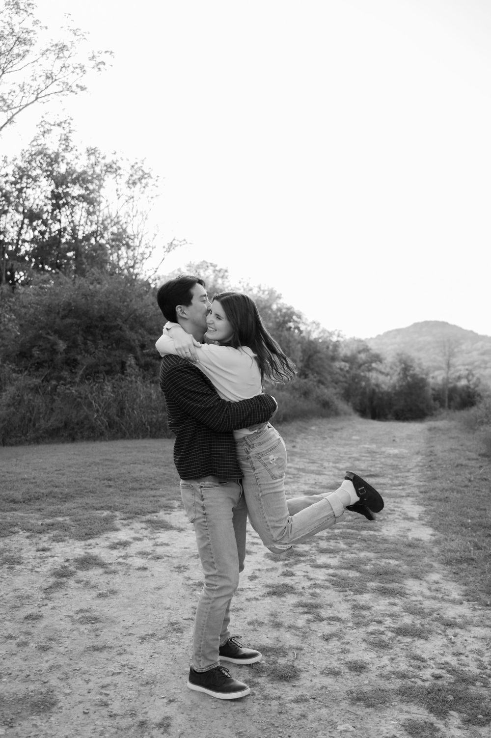 Black and white image of man lifting and spinning his fiancé
