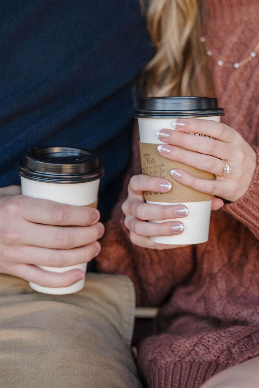 A detail shot of engaged couple holding coffee cups together