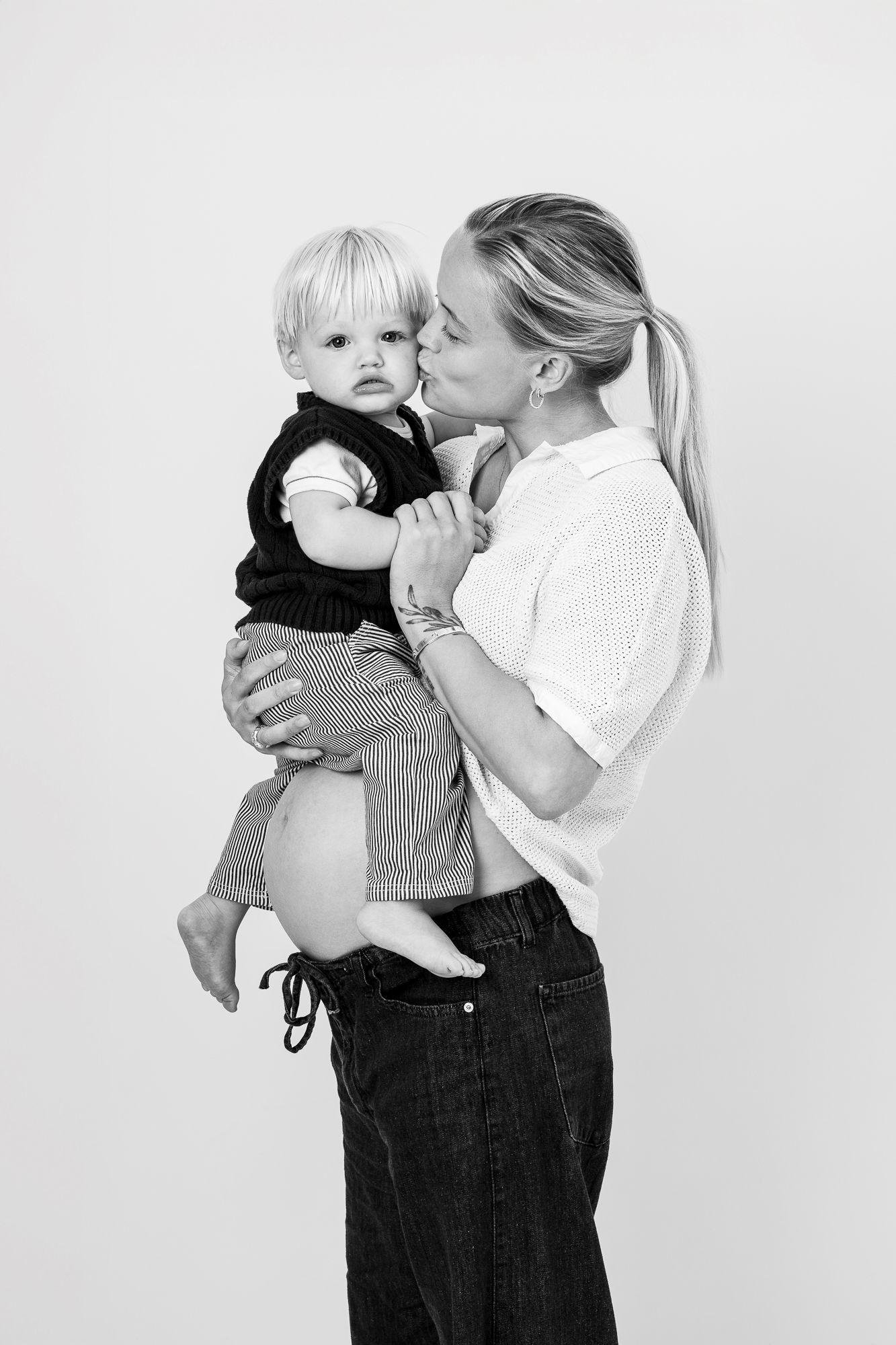 Black and white photo series showing tender embraces between a parent and young child against a plain backdrop.
