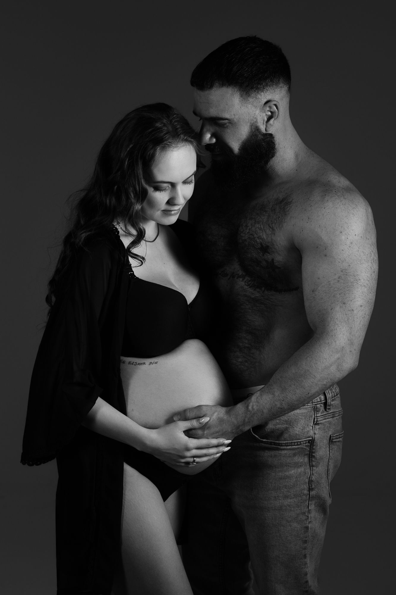 Artistic black and white maternity photo featuring an intimate moment between expectant couple.