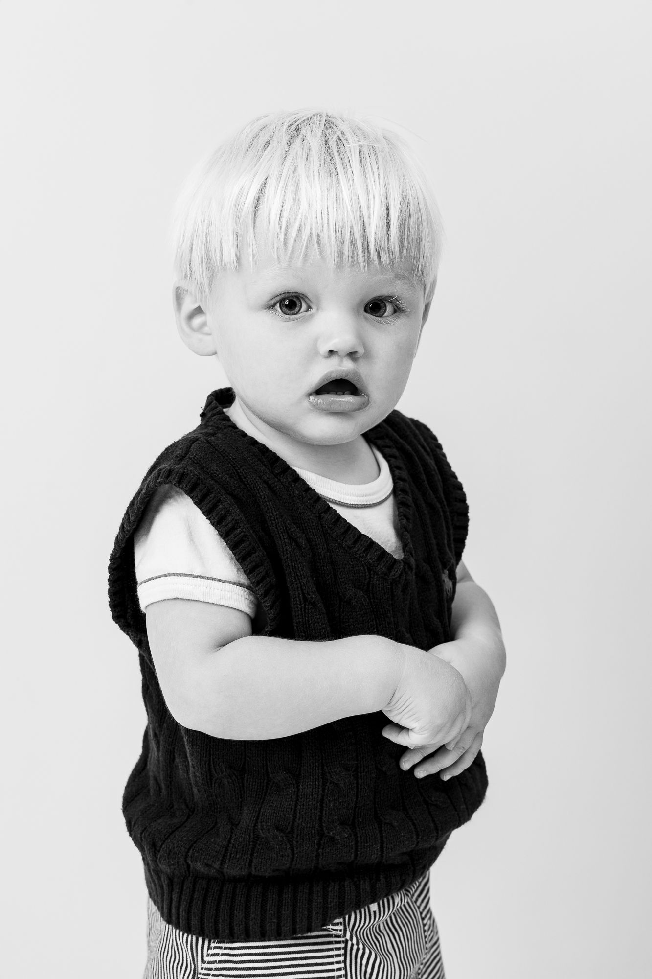 Four black and white photographs show a baby with blonde hair wearing a black ruffled dress in different poses.