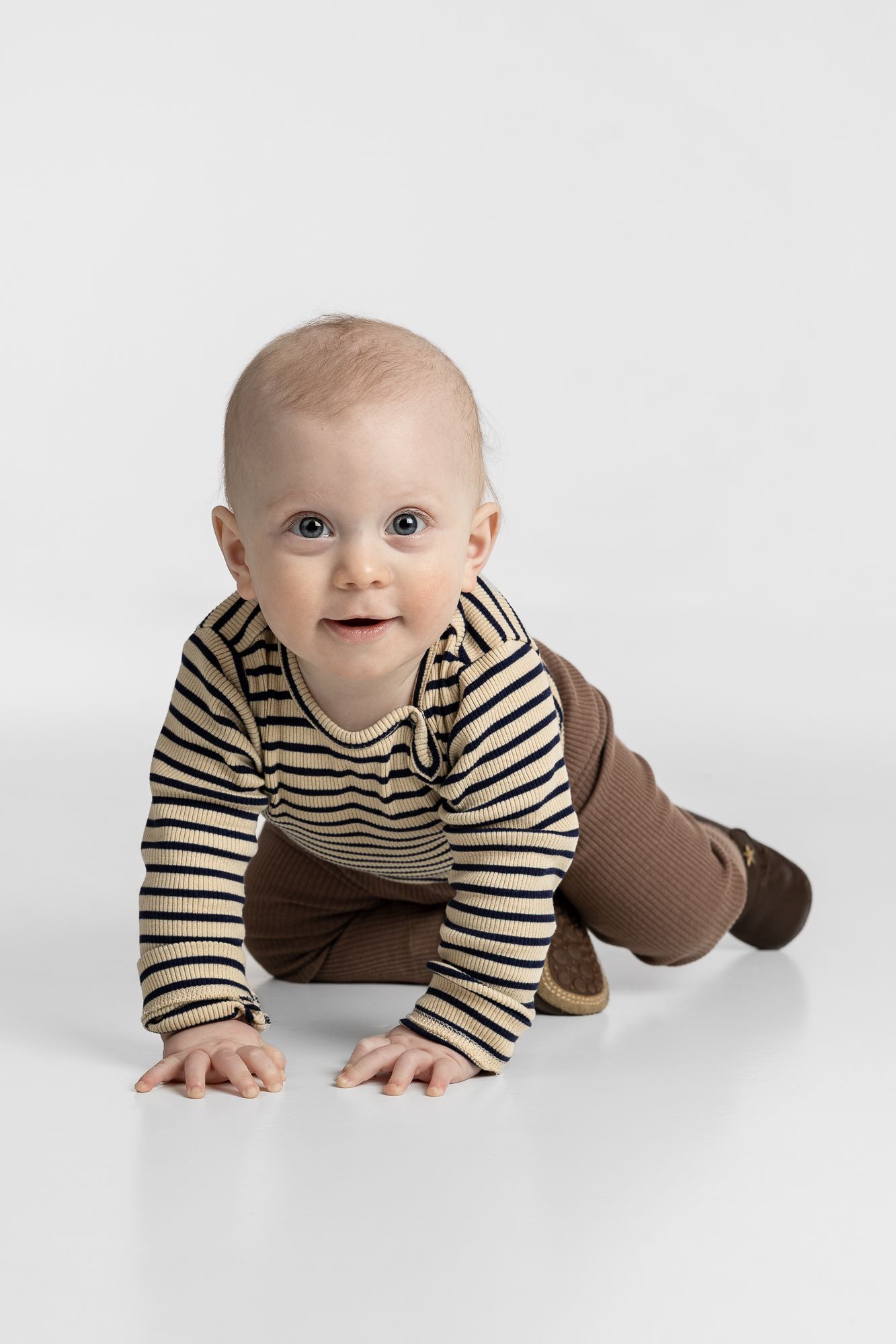 A crawling baby wearing a brown and cream striped outfit photographed in sequence from different angles.