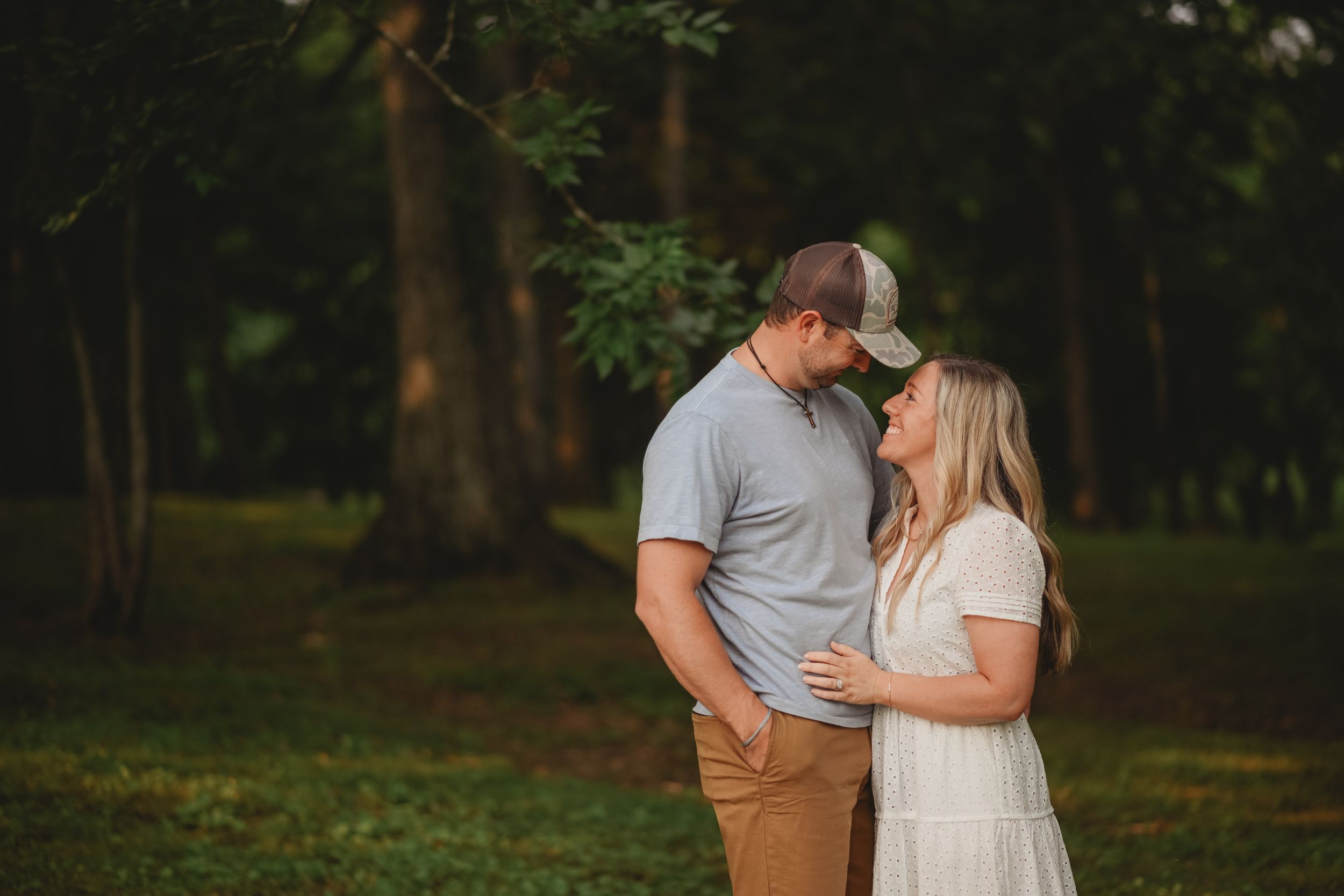 A couple sharing an intimate moment in a wooded setting.
