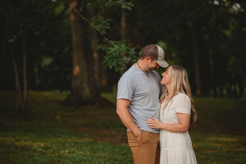 A couple sharing an intimate moment in a wooded setting.