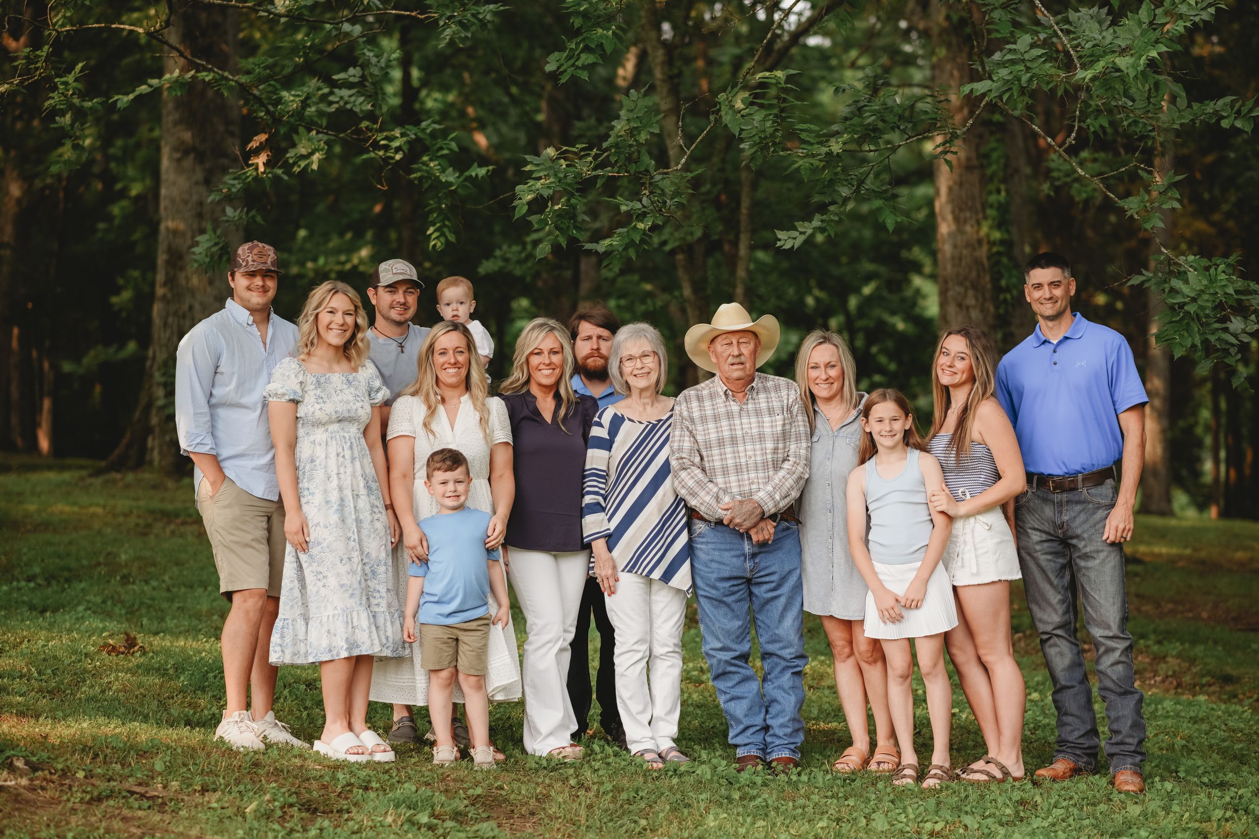 A large family group portrait outdoors with trees in the background.