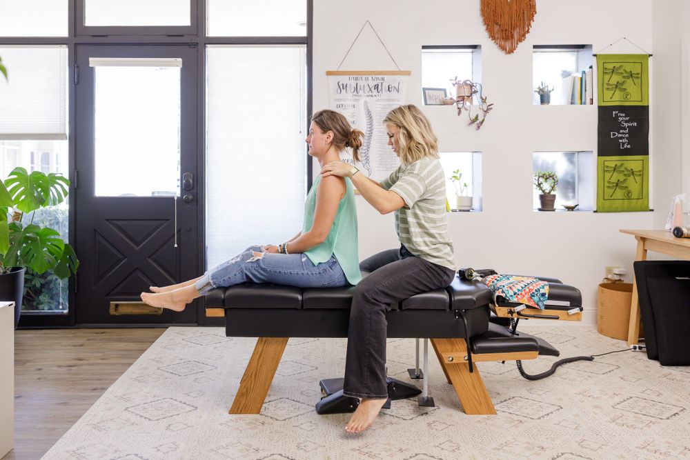 buoyant chiropractic woman practitioner in Tacoma, WA personal branding photo checking client while sitting on table