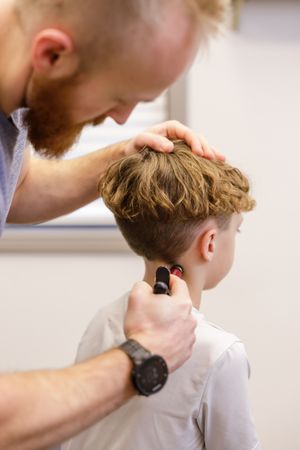 Limitless Chiropractic in Sumner WA personal branding photoshoot adjusting young boy with adjustment tool on upper neck while sitting up