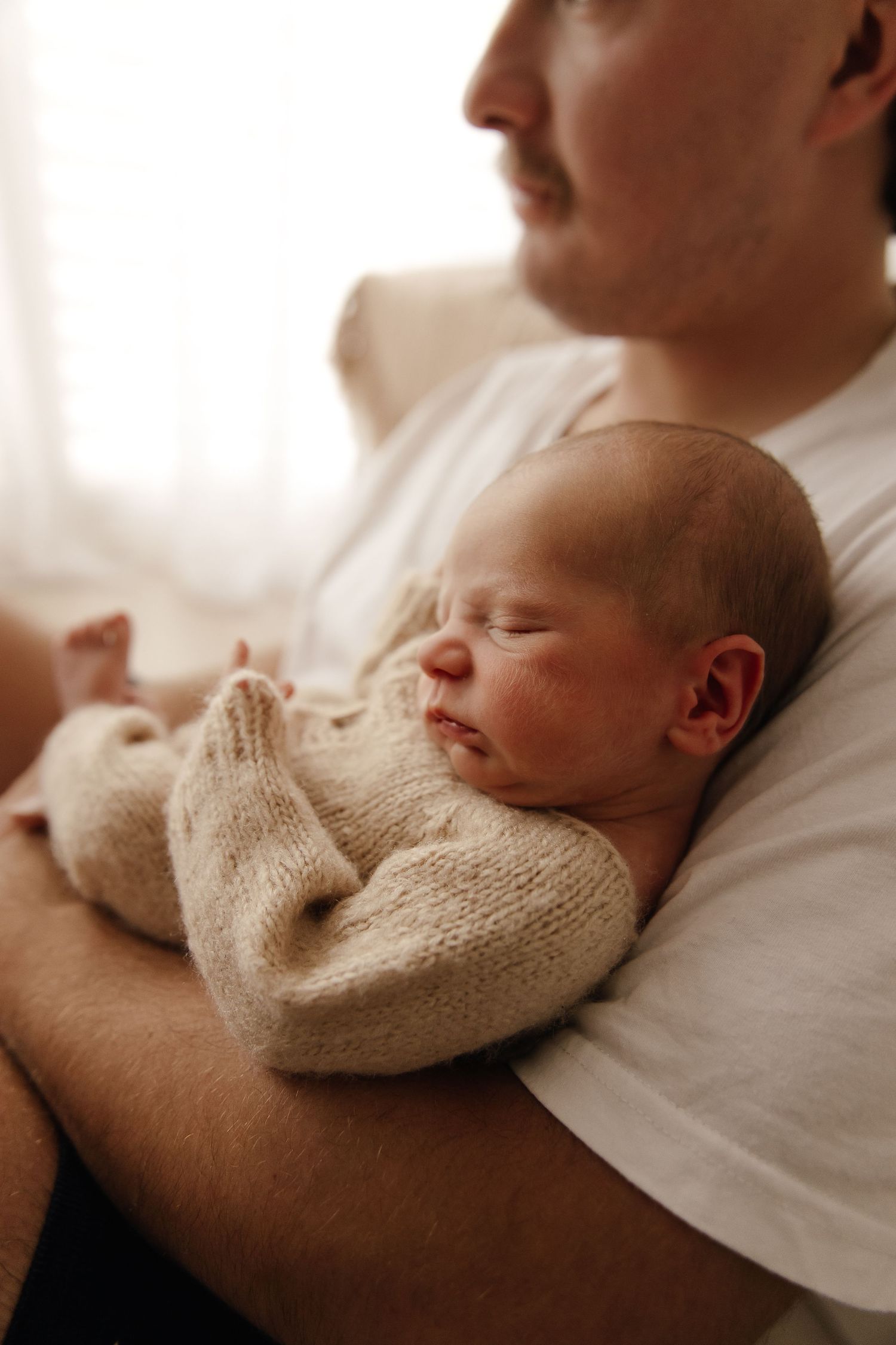 Close-up of tiny newborn baby feet being held by gentle hands.