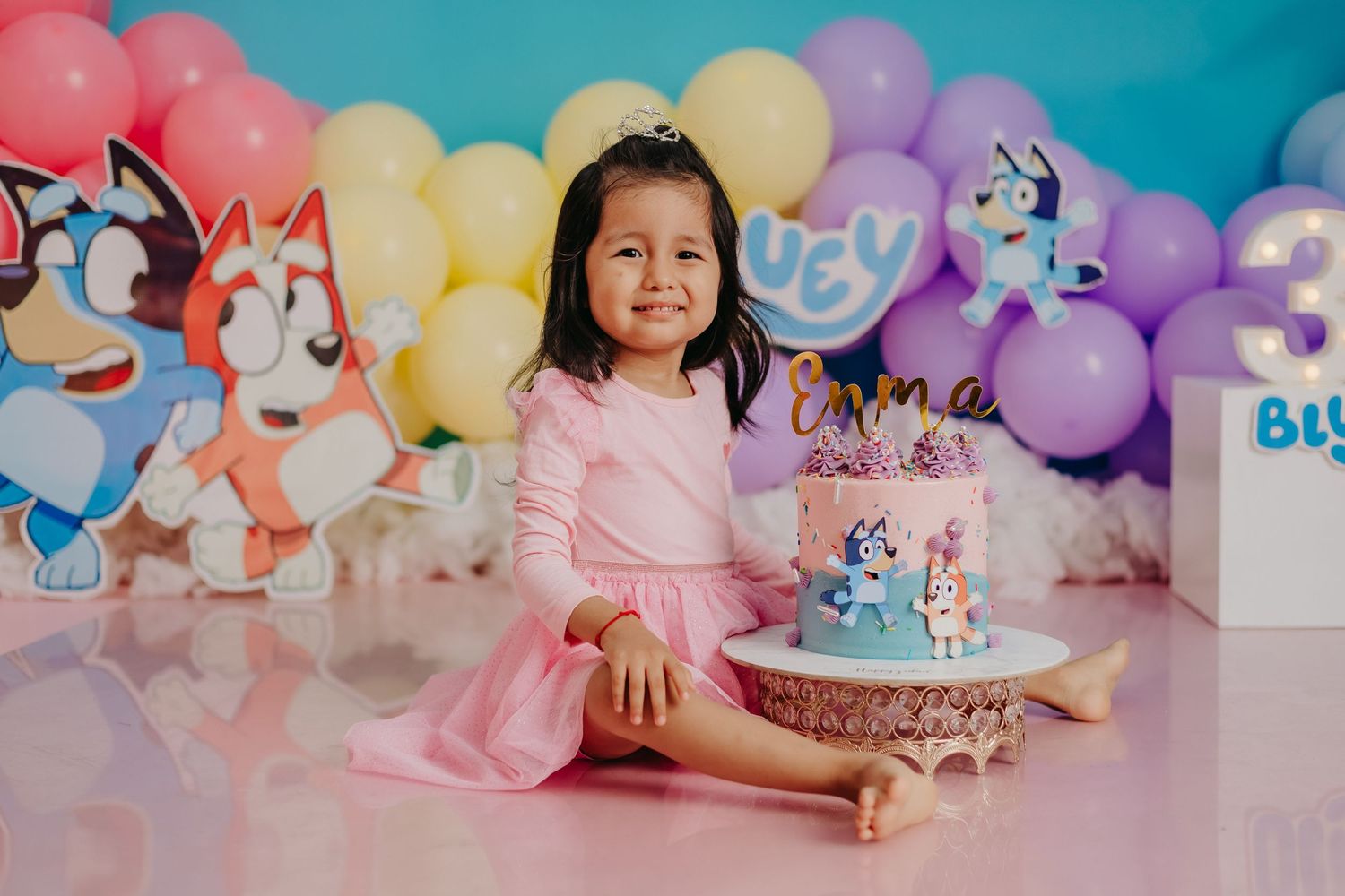 Pastel birthday party setup with unicorn decorations and multicolored balloon arch.