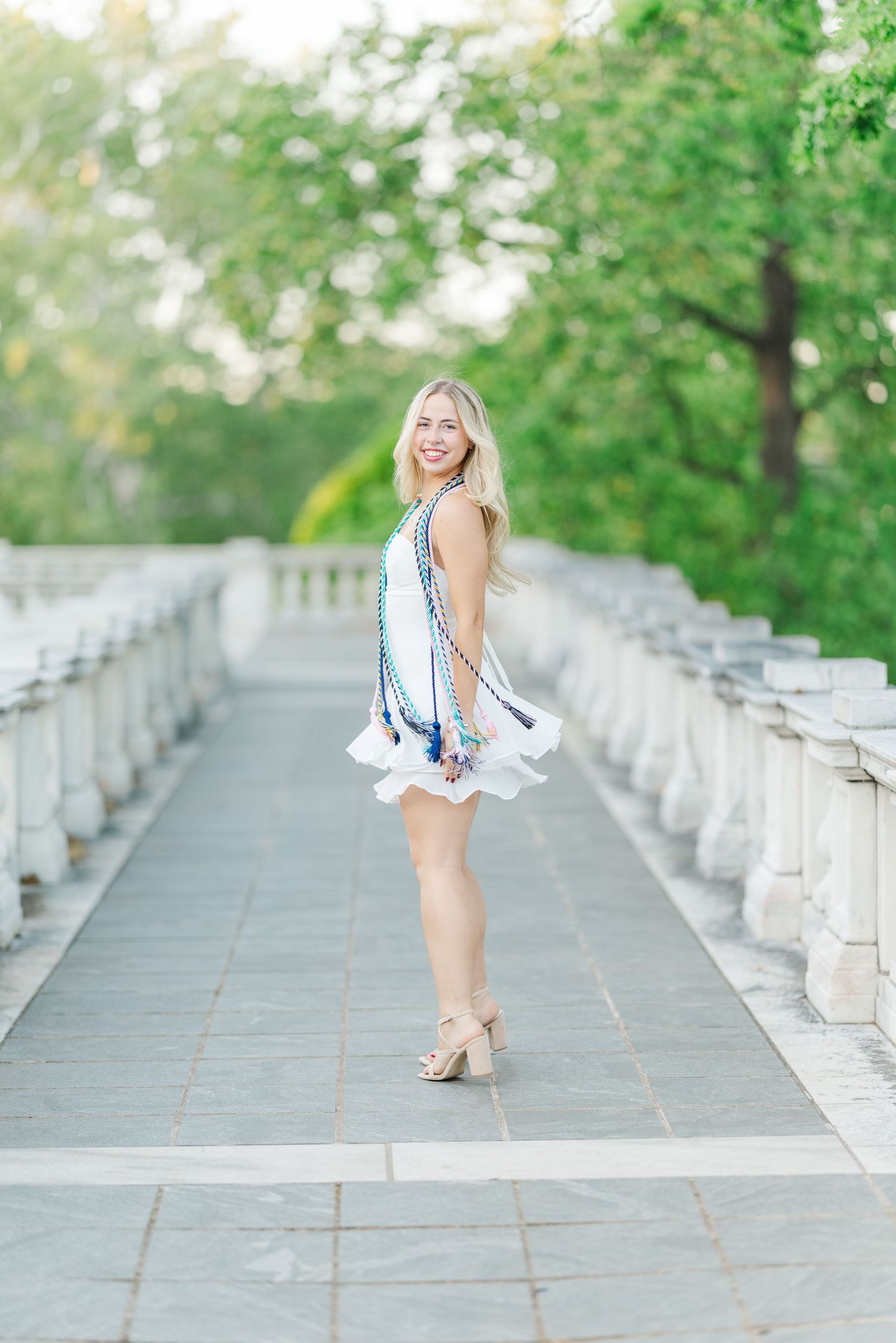 Young woman in a pink crop top and light jeans runs along a canal path under a stone bridge on a sunny day.