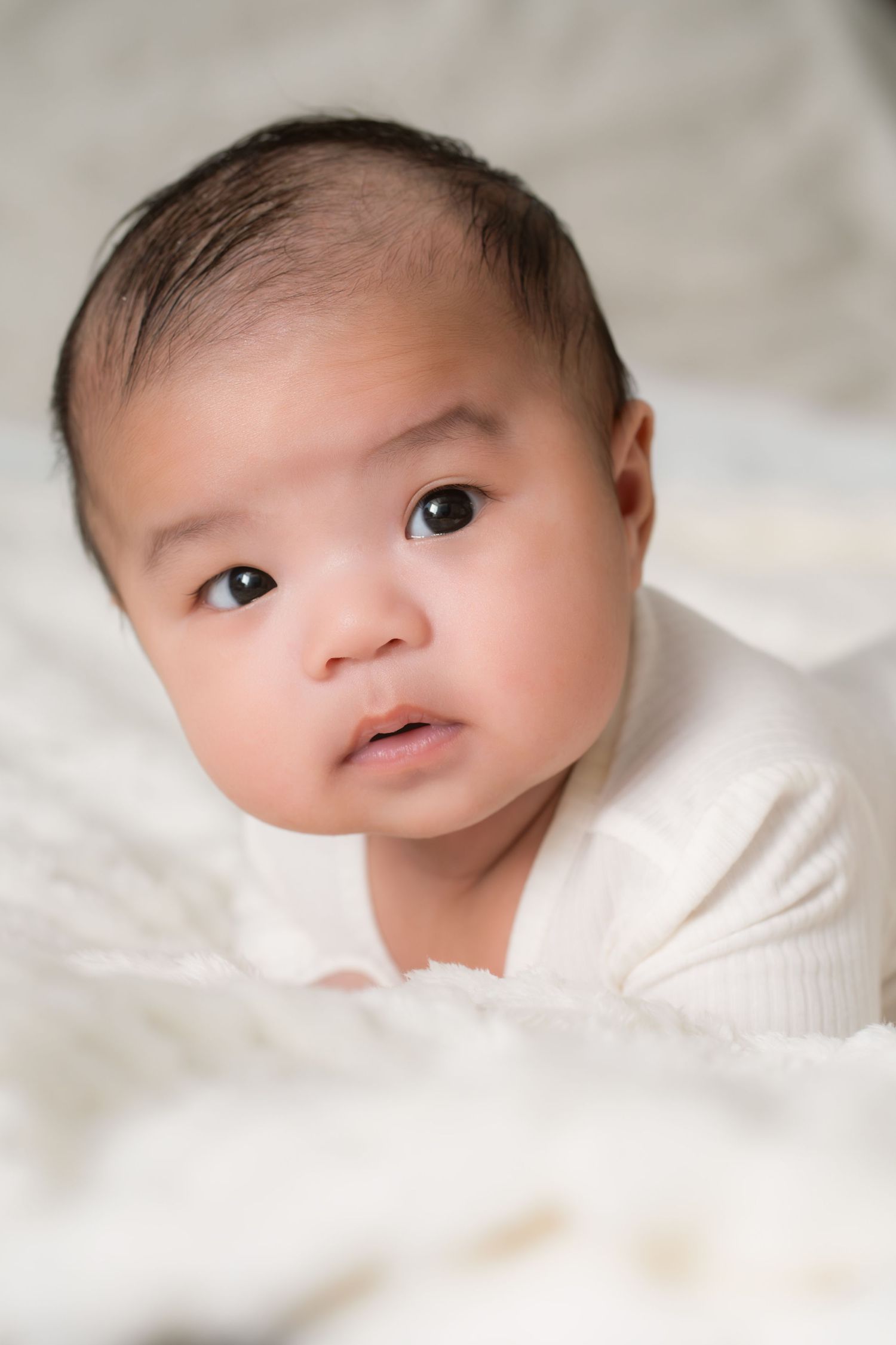 Baby in beige outfit lying on brown backdrop in various adorable poses.