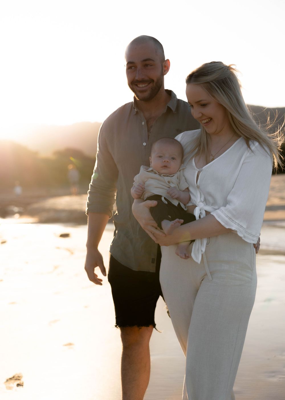 Mum, dad, and their baby sharing a peaceful cuddling moment at the local beach - family, newborn and baby outdoor photoshoot in Wollongong.