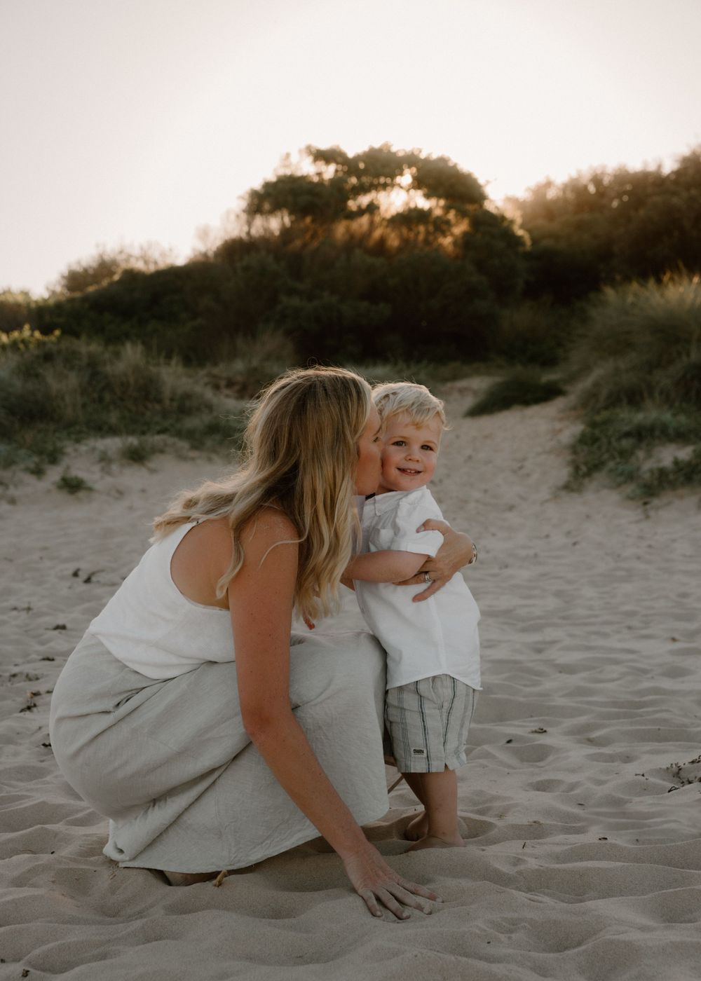 Mum holding toddler in arms, giving him a kiss, lovingly smiling at each other - baby and mother photography in Wollongong, Bulli, Woonona.