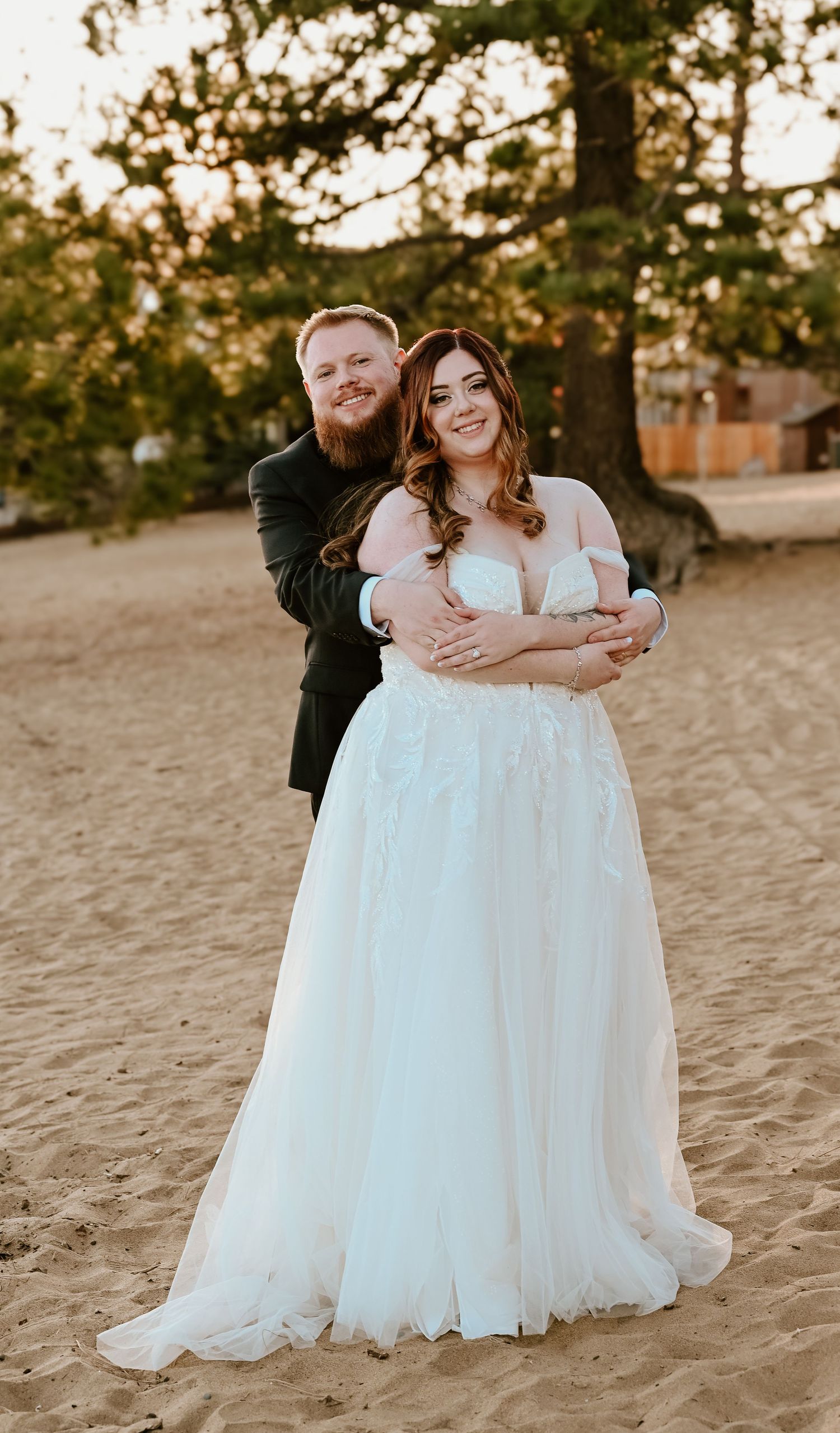 A couple poses for wedding photos on a wooden bridge during a golden sunset.