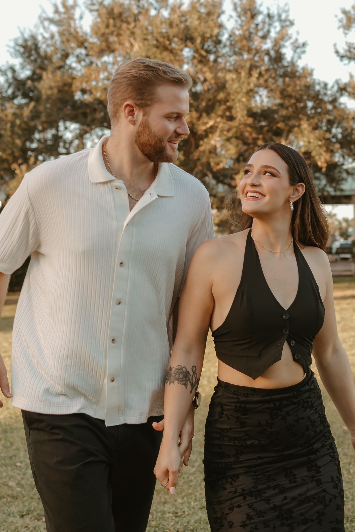 Couple in contrasting black and white outfits share intimate moments against an autumn backdrop.